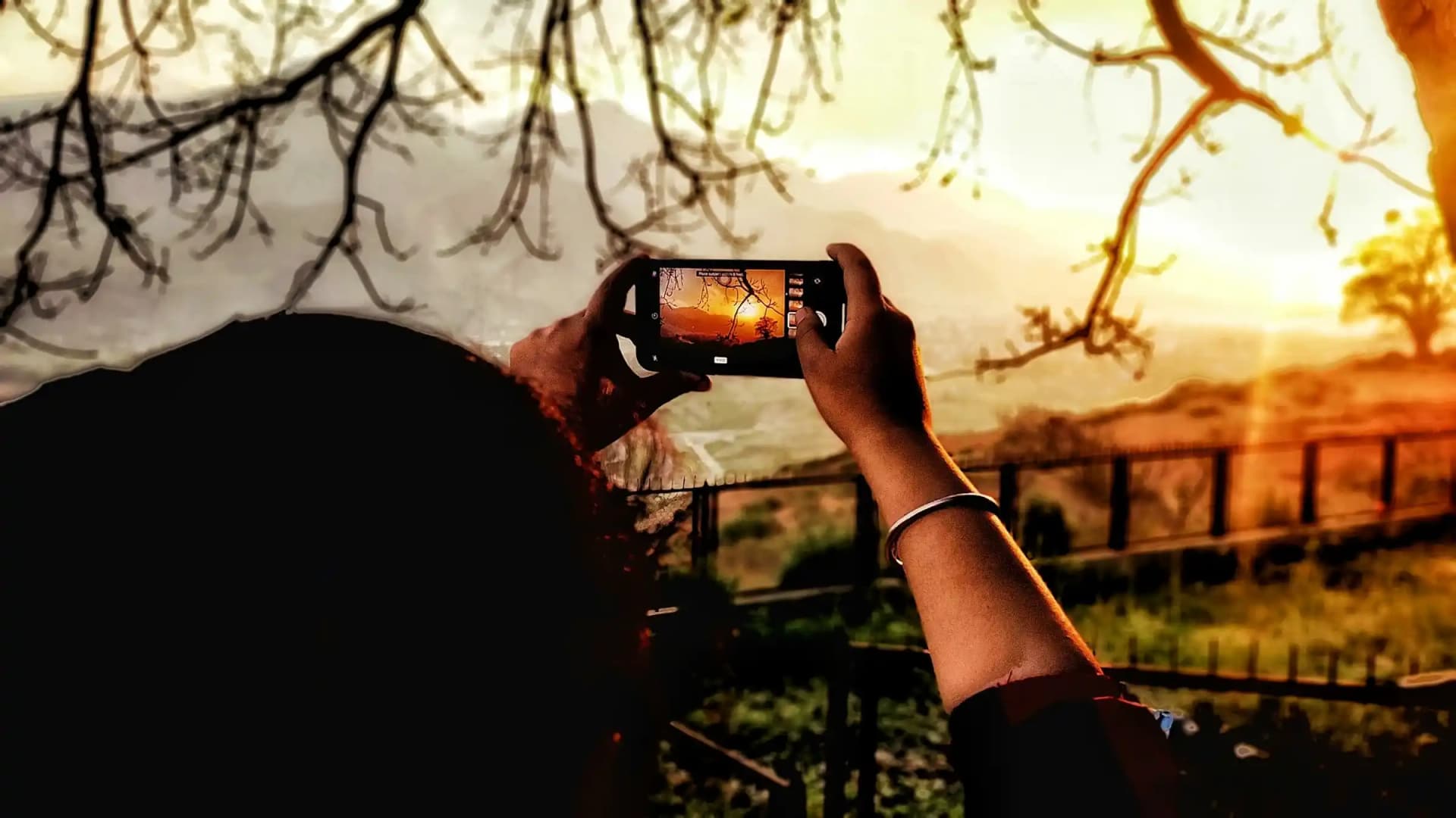 A guy trying to click sunset with his mobile phone under 40000